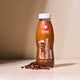 Maxi Shake Protein Coffee bottle with coffee beans on a beige background
