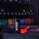Maxi Nutrition shaker cup with a red cap on a gym floor with weights in the background