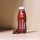 Maxi Nutrition MaxShake Protein Shake Chocolate bottle with chocolate pieces on a beige background