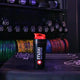 Maxi Nutrition shaker bottle on a gym towel with dumbbells and weight plates in the background