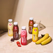 Maxi Shake bottles in various flavors with bananas on a beige surface