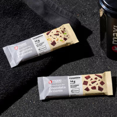 Two protein bars with a MaxiNutrition shaker bottle on a dark surface